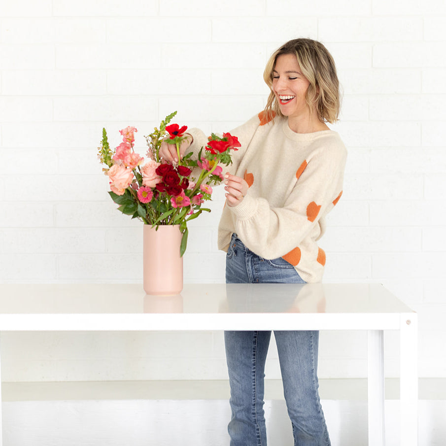 Woman arranging flowers in pink vase