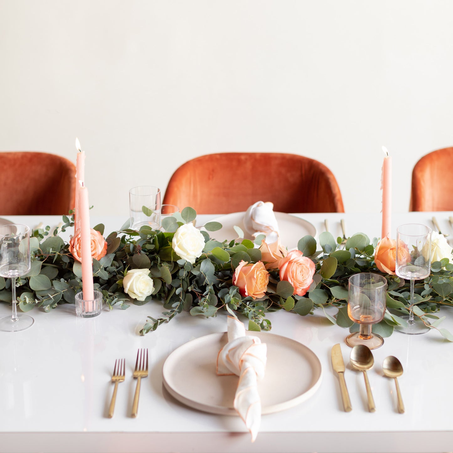 Eucalyptus Rose garland on formal table with peach taper candles