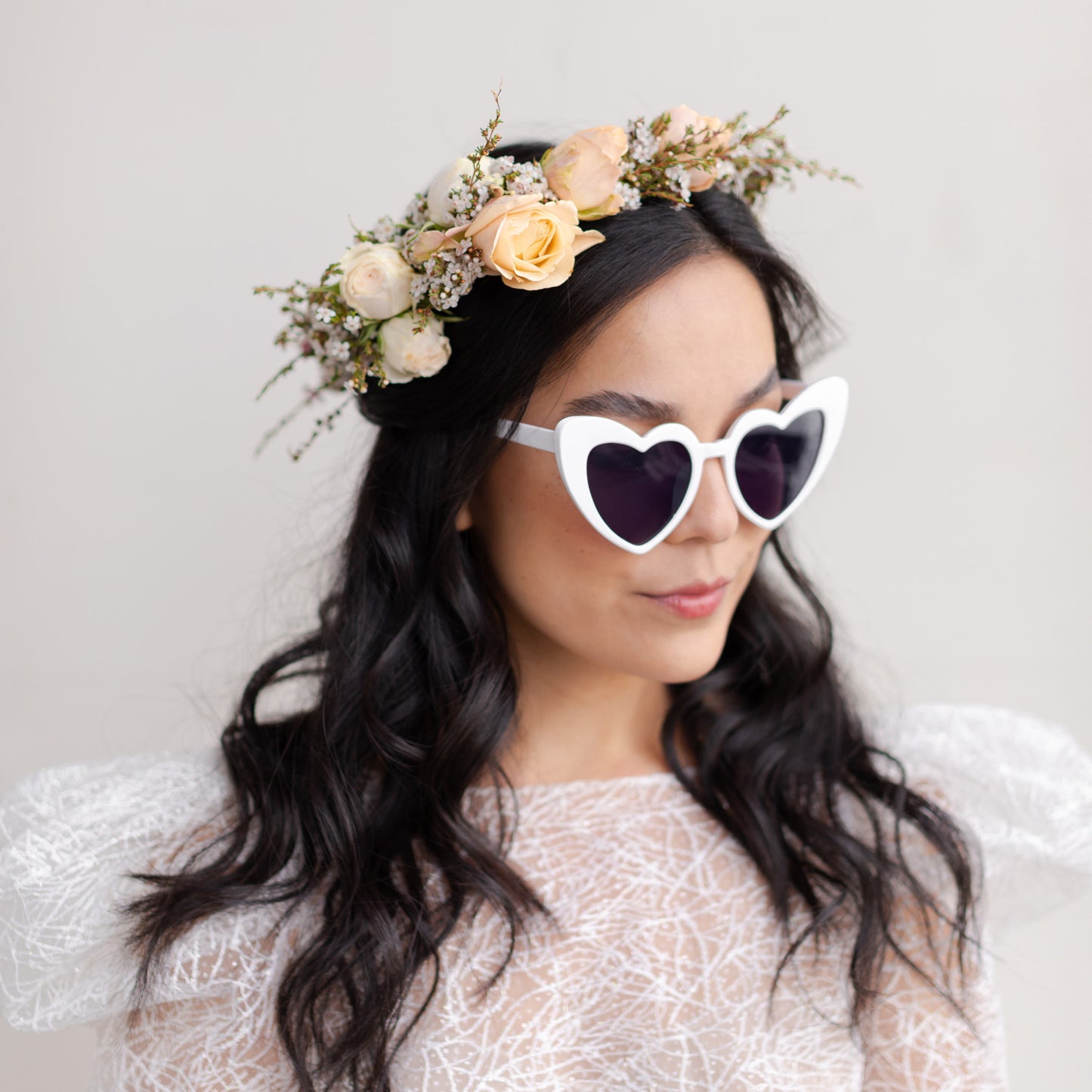 Woman with dark hair wearing Grace flower crown and heart sunglasses