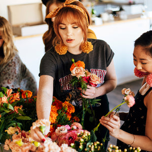 Woman with red hair arranges flowers in a group setting