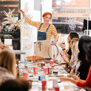 Woman holding a dried flower wreath at the head of a classroom